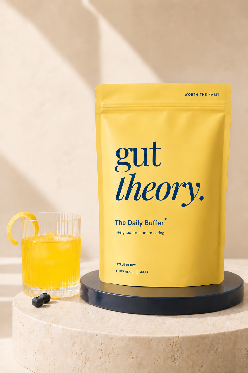 The Daily Buffer Citrus Berry 300 g pouch beside a yellow drink; packaging visualisation.
